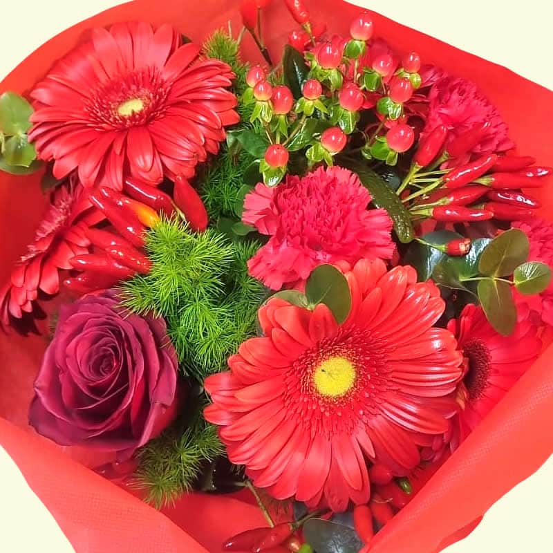 Un allegro bouquet sui toni del rosso. Consegniamo a domicilio in giornata